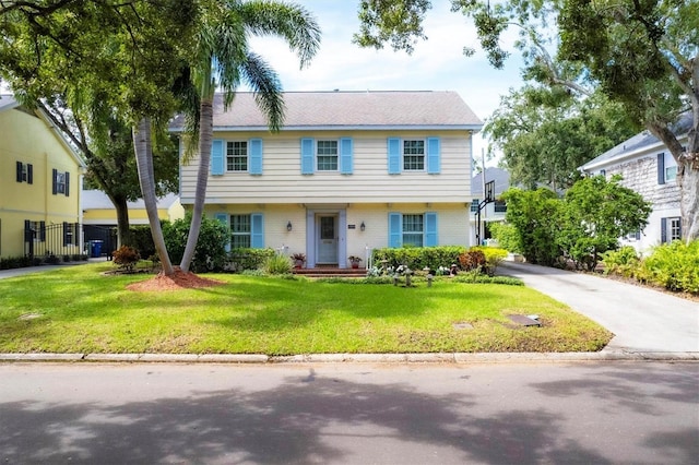 colonial-style house with brick siding, driveway, and a front lawn