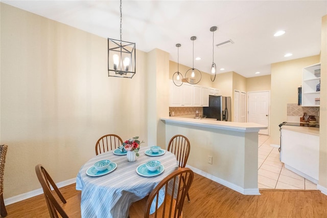 dining space with light hardwood / wood-style flooring and a notable chandelier