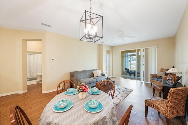 dining room featuring light wood-type flooring and ceiling fan with notable chandelier