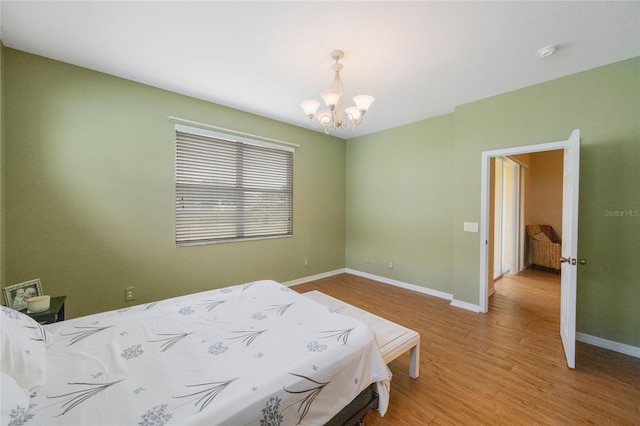 bedroom with light hardwood / wood-style floors and a notable chandelier