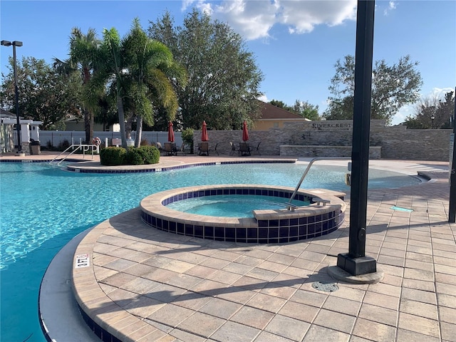 view of swimming pool with a hot tub and a patio area