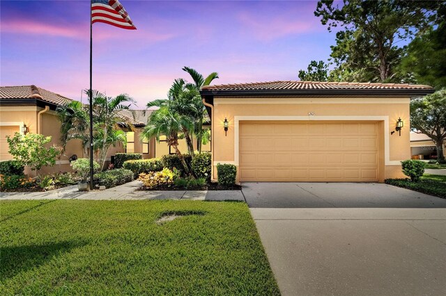 mediterranean / spanish-style house with a garage and a lawn