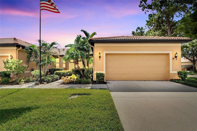 view of front facade with a tile roof, stucco siding, driveway, a front lawn, and a garage
