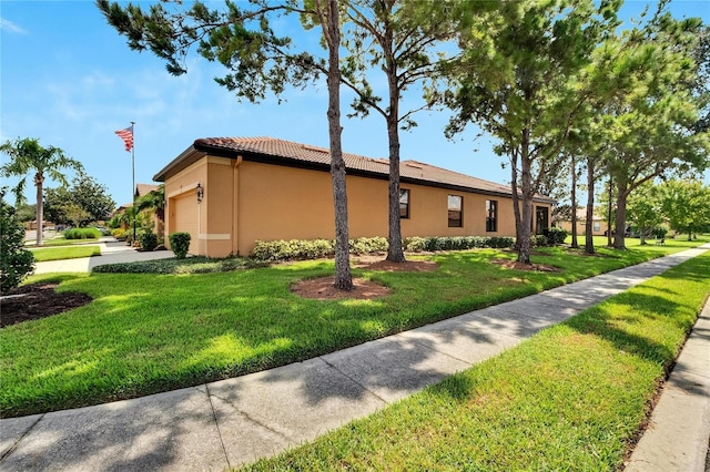 view of side of home featuring stucco siding, an attached garage, a tile roof, and a yard