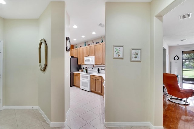 kitchen with light countertops, visible vents, white appliances, baseboards, and light tile patterned floors