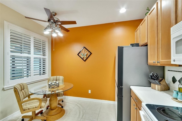 kitchen with decorative backsplash, baseboards, a ceiling fan, white microwave, and light tile patterned floors