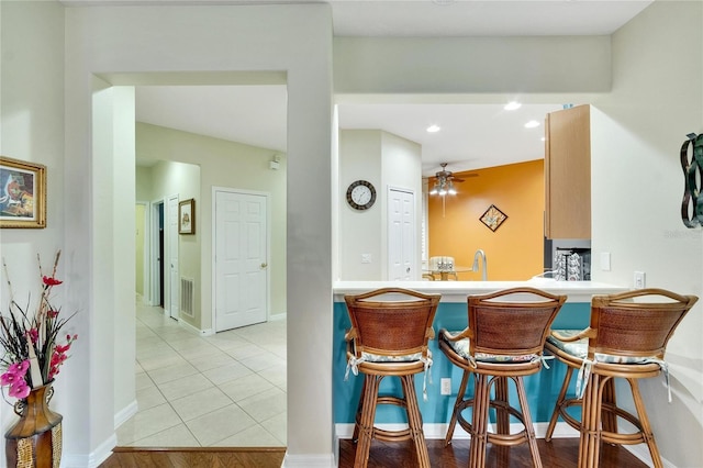 kitchen featuring a kitchen breakfast bar, recessed lighting, light tile patterned flooring, visible vents, and ceiling fan