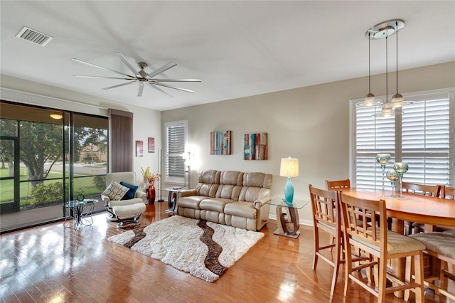 living area featuring wood finished floors, baseboards, ceiling fan, and visible vents