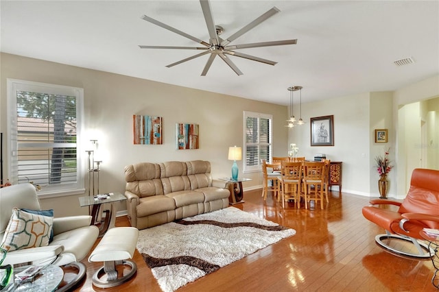 living area with a ceiling fan, hardwood / wood-style flooring, baseboards, and visible vents