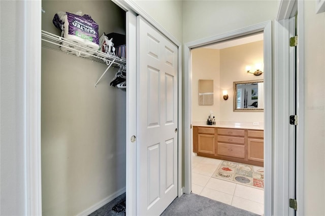 bathroom with tile patterned flooring, a spacious closet, and vanity