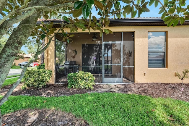 back of house featuring stucco siding, a tile roof, and ceiling fan