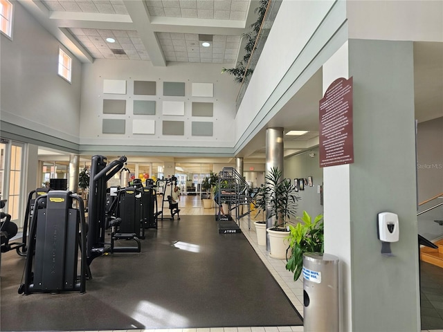 gym featuring a towering ceiling and coffered ceiling