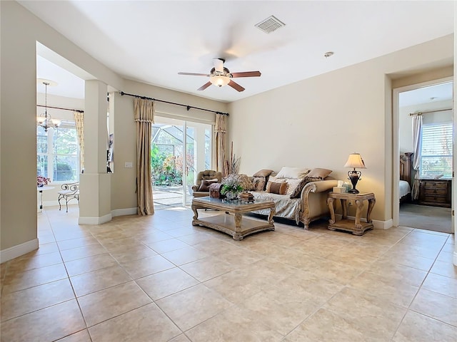 tiled living room with ceiling fan with notable chandelier