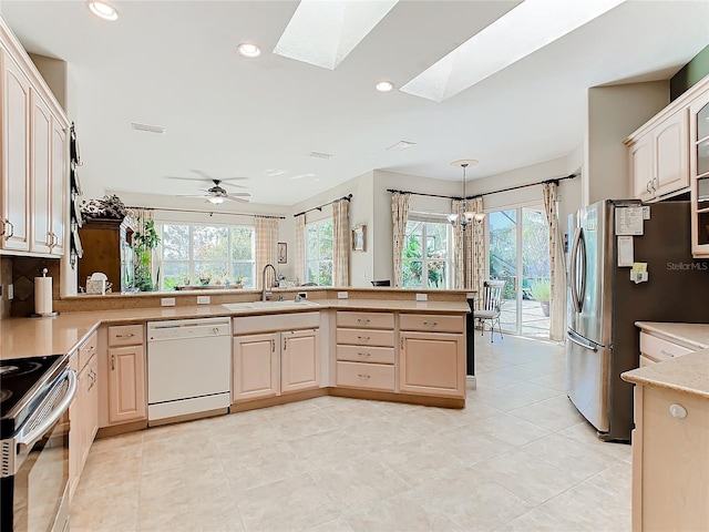 kitchen featuring ceiling fan with notable chandelier, sink, a skylight, kitchen peninsula, and stainless steel appliances