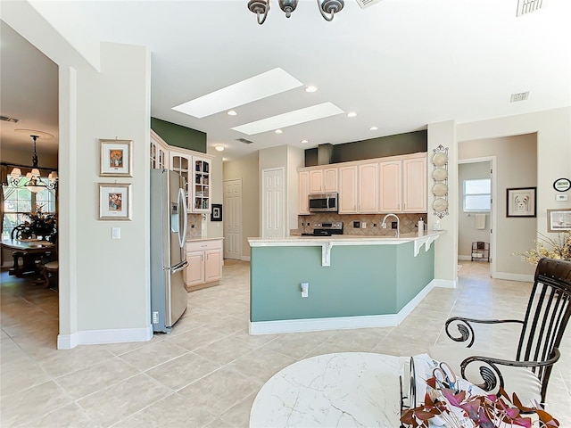 kitchen featuring a skylight, stainless steel appliances, tasteful backsplash, kitchen peninsula, and plenty of natural light