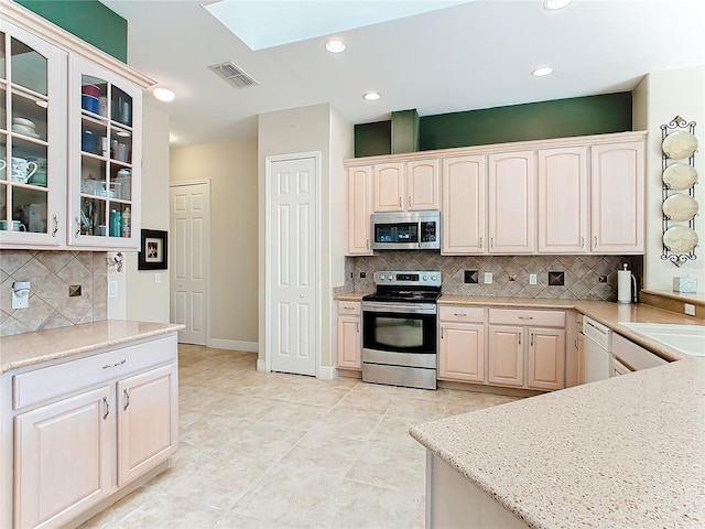 kitchen with tasteful backsplash, a skylight, sink, and stainless steel appliances