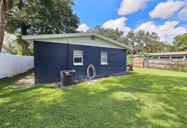 rear view of house with central AC and a lawn