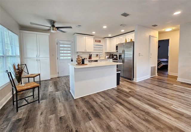 kitchen with white cabinets, ceiling fan, hardwood / wood-style flooring, stainless steel appliances, and a center island