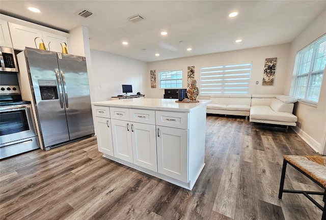 kitchen featuring dark hardwood / wood-style floors, stainless steel appliances, a kitchen island, and white cabinets