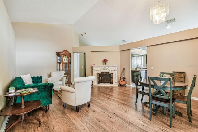 living room featuring an inviting chandelier, light wood-type flooring, lofted ceiling, and a fireplace