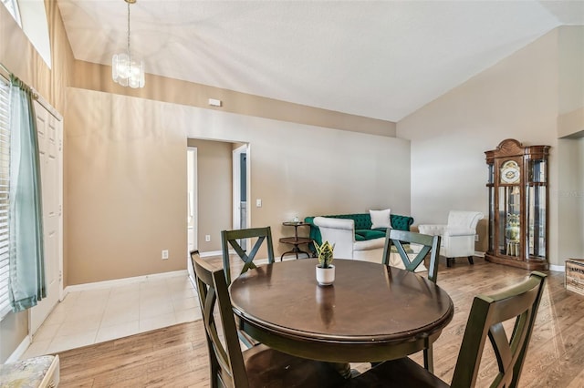 dining room featuring an inviting chandelier, light wood-type flooring, and high vaulted ceiling