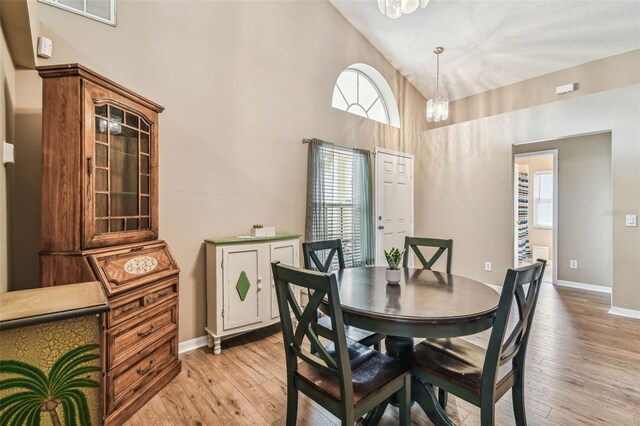 dining room featuring high vaulted ceiling, a chandelier, and light hardwood / wood-style floors