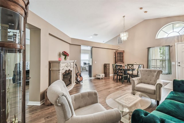 living room featuring light wood-type flooring, lofted ceiling, plenty of natural light, and a high end fireplace