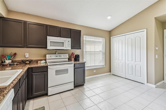 kitchen with dark brown cabinets, sink, vaulted ceiling, white appliances, and light tile patterned floors