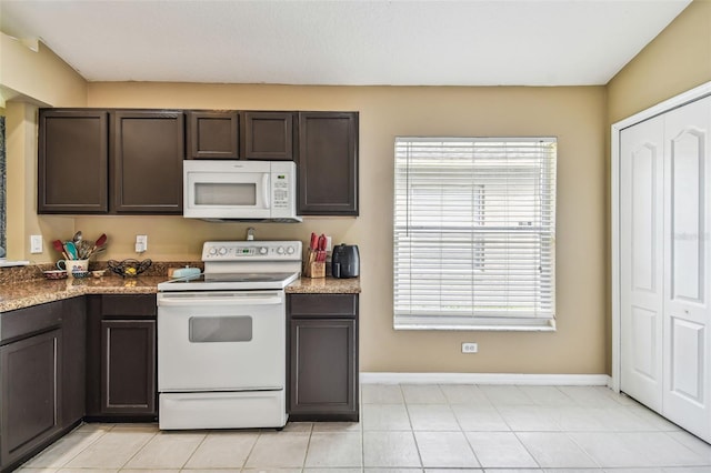 kitchen with dark brown cabinetry, white appliances, and light tile patterned floors