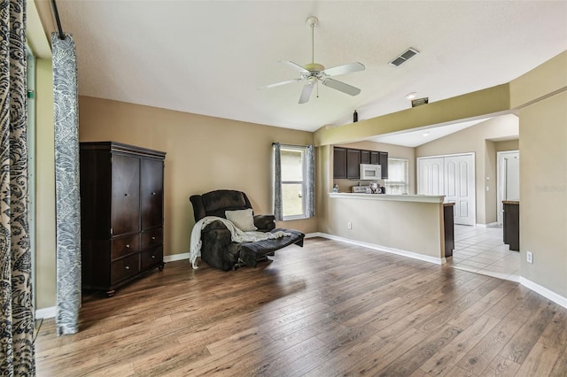 living area featuring lofted ceiling, light hardwood / wood-style floors, and ceiling fan