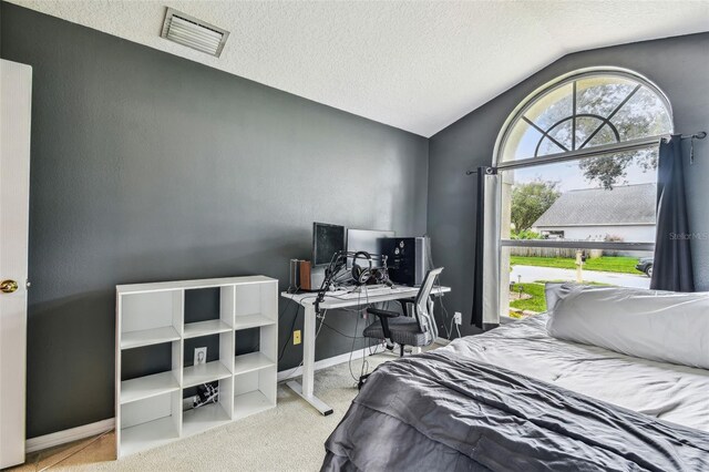 bedroom with a textured ceiling, vaulted ceiling, and light colored carpet