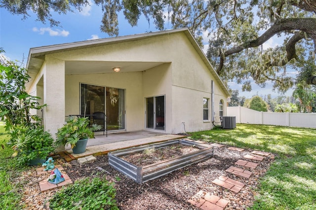 rear view of house with a patio, a yard, and central AC