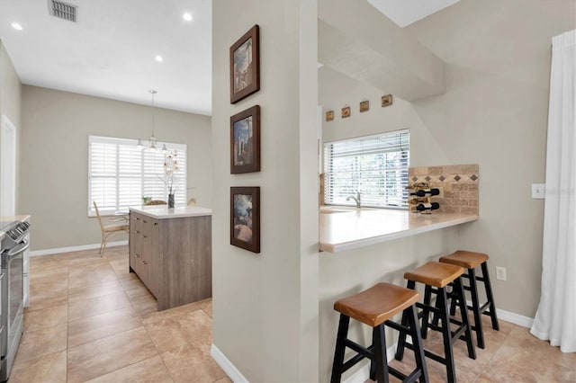 kitchen featuring kitchen peninsula, a breakfast bar area, plenty of natural light, and light tile patterned floors