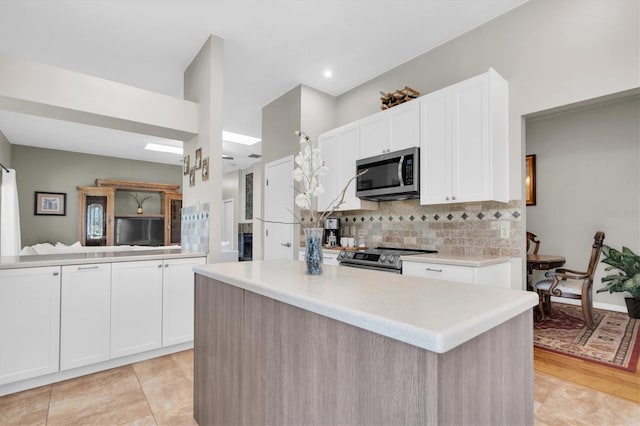 kitchen with appliances with stainless steel finishes, white cabinets, a center island, and light hardwood / wood-style floors