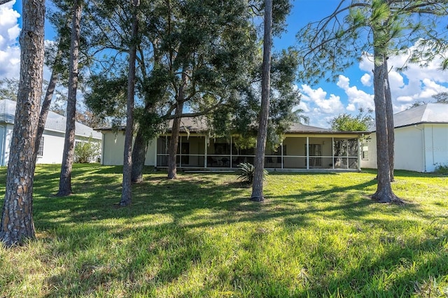 rear view of house with a yard and a sunroom