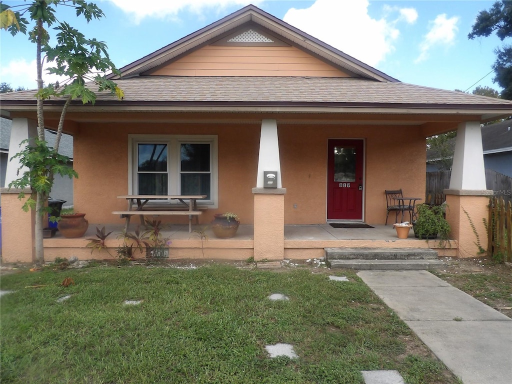 view of front of home with covered porch and a front lawn