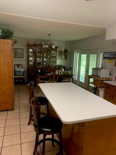 kitchen with a kitchen breakfast bar, light tile patterned floors, and a chandelier