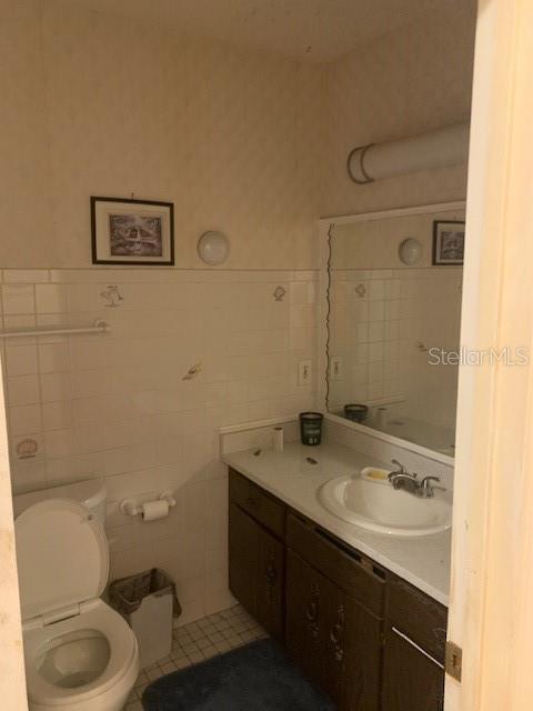 bathroom featuring tile walls, vanity, and toilet