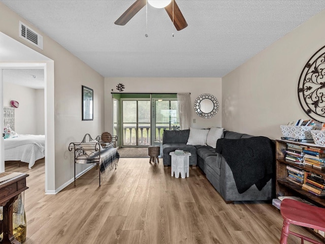 living room featuring light hardwood / wood-style floors, a textured ceiling, and ceiling fan