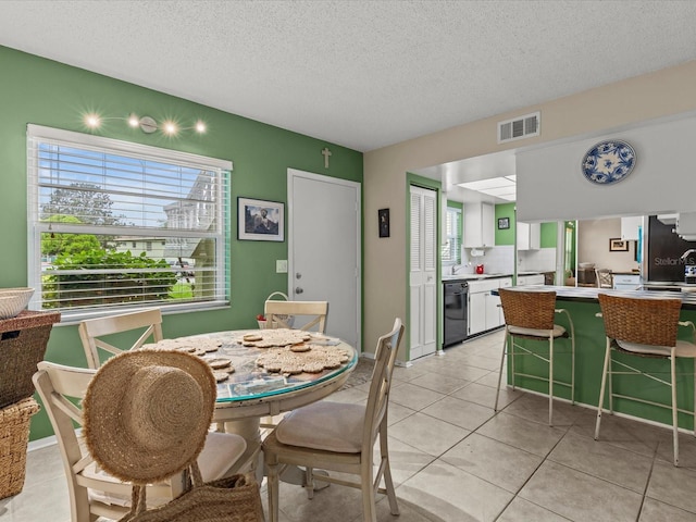 dining room featuring sink, light tile patterned floors, and a textured ceiling