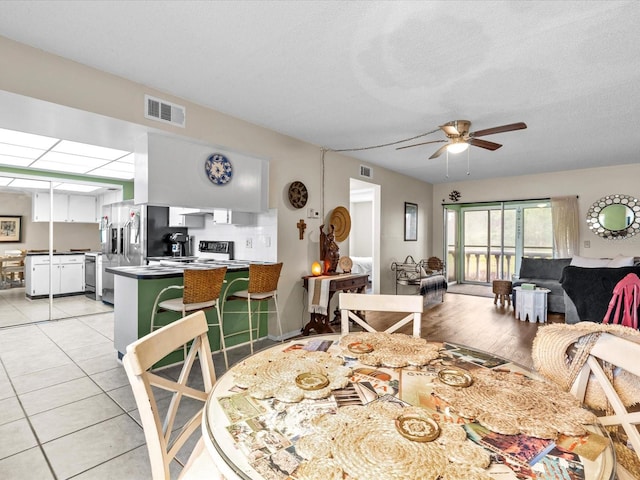 tiled dining space with a textured ceiling and ceiling fan