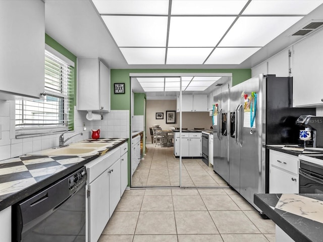 kitchen featuring light tile patterned flooring, tasteful backsplash, sink, white cabinets, and black appliances