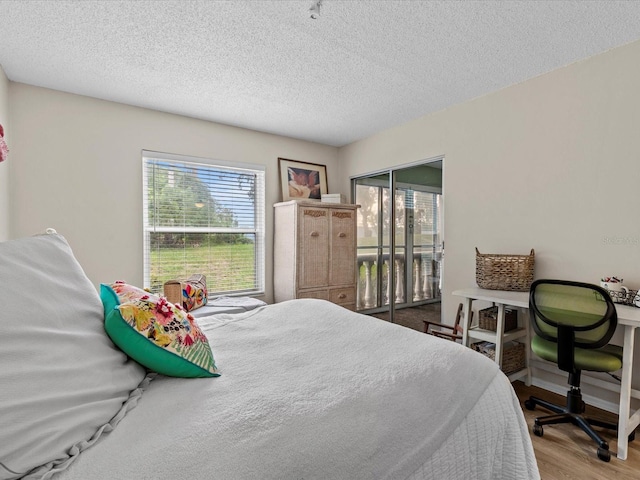 bedroom featuring access to outside, hardwood / wood-style flooring, and a textured ceiling