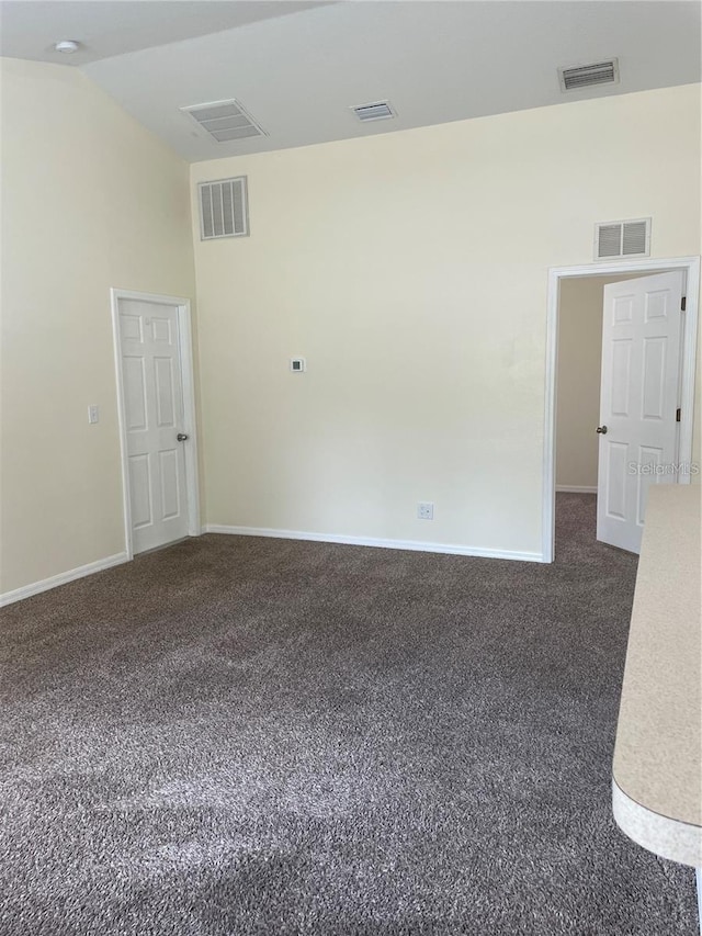 empty room with lofted ceiling and dark colored carpet