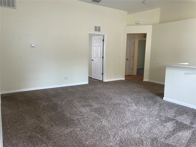 unfurnished room featuring vaulted ceiling and dark carpet