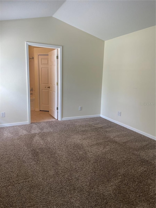 carpeted spare room featuring vaulted ceiling