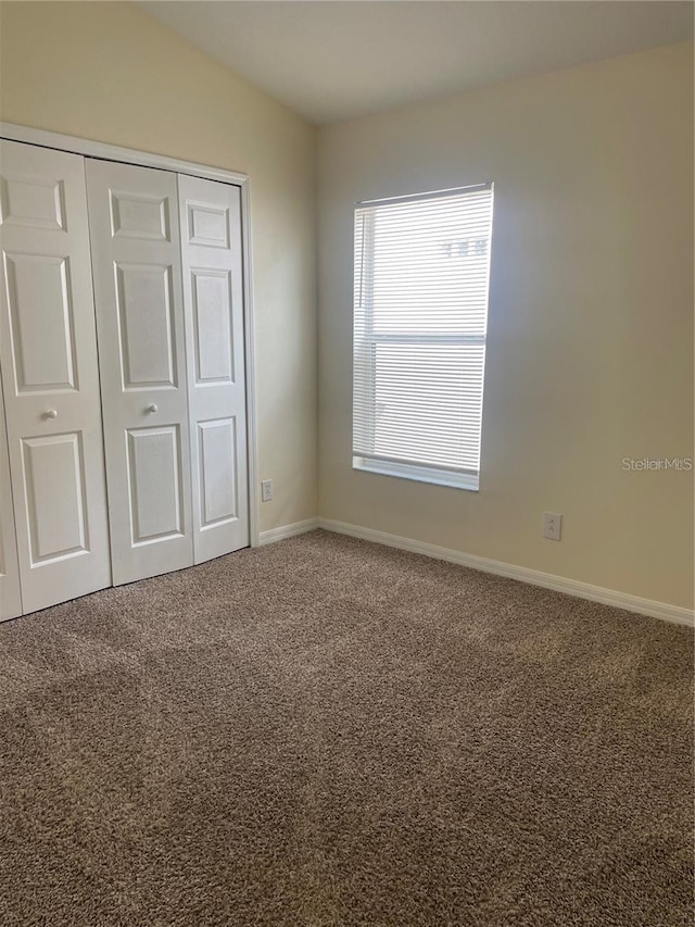 unfurnished bedroom featuring carpet floors, a closet, and vaulted ceiling