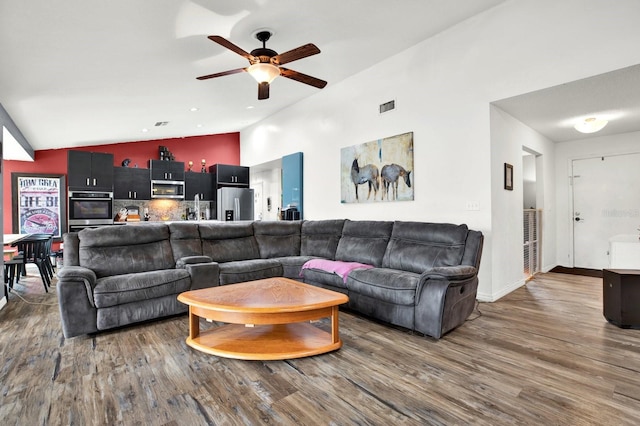 living room with ceiling fan, dark hardwood / wood-style flooring, and vaulted ceiling