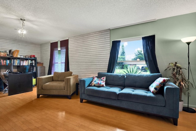 living room featuring a notable chandelier, light wood-type flooring, and a textured ceiling