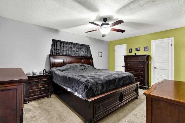 bedroom with ceiling fan, light colored carpet, and a textured ceiling